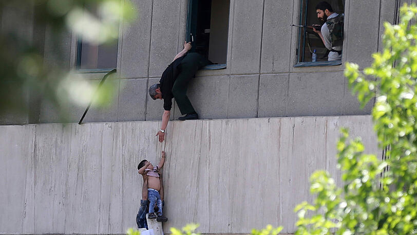 Menschen klettern aus einem Fenster in Parlament in Teheran. Bewaffnete Männer haben das Mausoleum des verstorbenen Revolutionsführers Ruhollah Chomeni sowie das Parlament gestürmt.