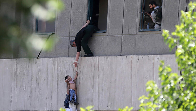 Menschen klettern aus einem Fenster in Parlament in Teheran. Bewaffnete Männer haben das Mausoleum des verstorbenen Revolutionsführers Ruhollah Chomeni sowie das Parlament gestürmt. Menschen klettern aus einem Fenster in Parlament in Teheran. Bewaffnete Männer haben das Mausoleum des verstorbenen Revolutionsführers Ruhollah Chomeni sowie das Parlament gestürmt.