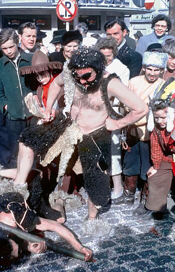 Faschingstreiben 1955 am Viktualienmarkt: Ein Neandertaler treibt es hier gerade besonders bunt.