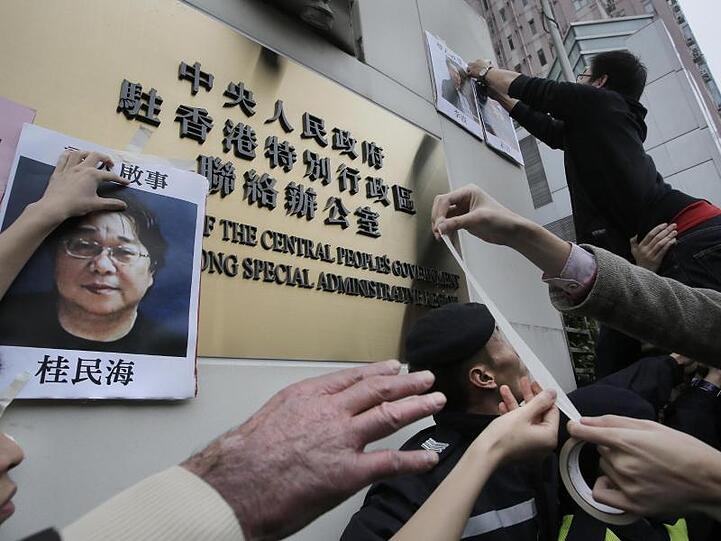 Demonstranten versuchen bei einer Kundgebung ein Foto des Hongkonger Buchhändlers Gui Minhai aus Protest gegen seine Verhaftung am Regierungssitz zu befestigen.