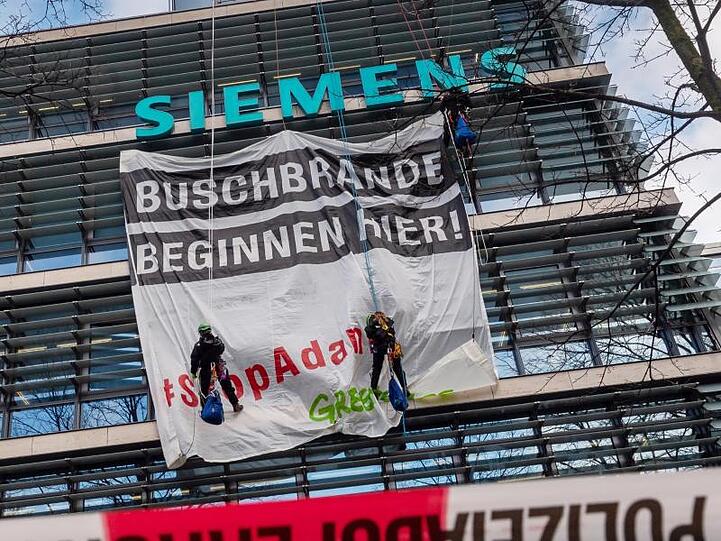 Aktivisten von Greenpeace hängen an der Fassade der Siemens-Zentrale ein Transparent. Foto: Peter Kneffel/dpa