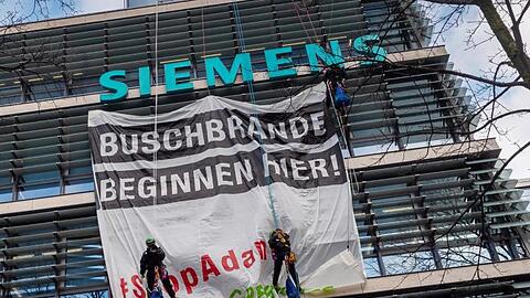 Aktivisten von Greenpeace hängen an der Fassade der Siemens-Zentrale ein Transparent. Foto: Peter Kneffel/dpa