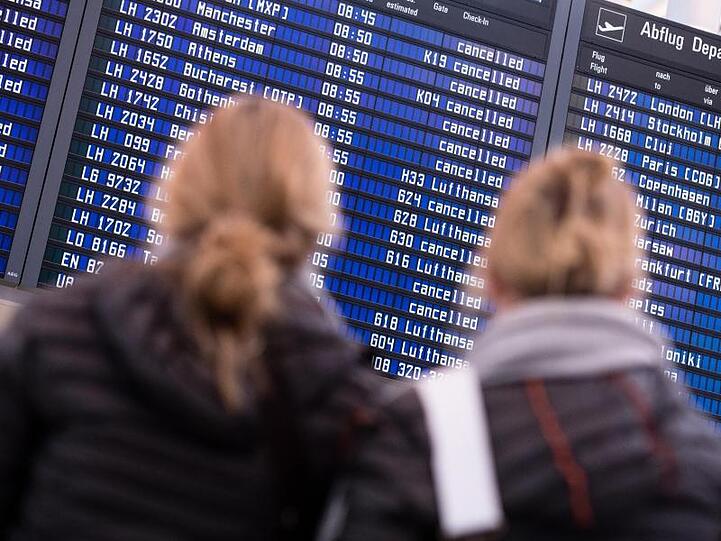 Zwei Frauen blicken auf dem Flughafen in München auf Anzeigetafeln. Foto: picture alliance / Matthias Balk/dpa / Archivbild