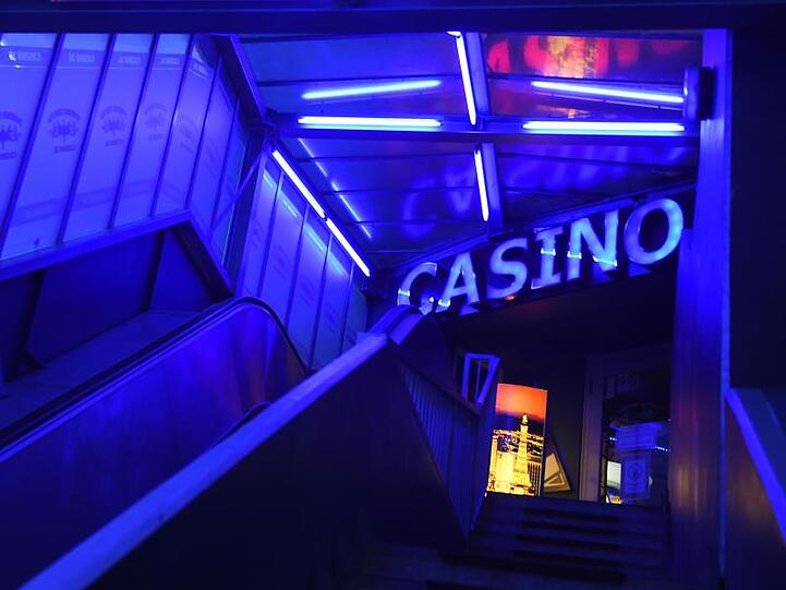 Der Eingang eines Kasinos strahlt in blauem Neonlicht. Foto: Sonja Wurtscheid/dpa/Symbolbild