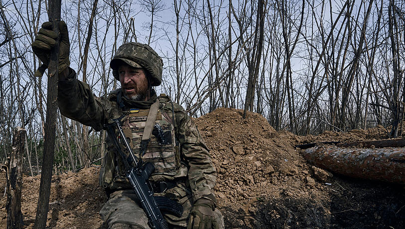 Ein ukrainischer Soldat schaut aus einem Schützengraben an der Frontlinie in Bachmut.