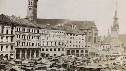 Kustermann (zweites Haus v.l.) gehörte schon 1895 zum Viktualienmarkt wie das Gemüse. Die Häuserreihe hat sich seitdem kaum verändert. Die Standl auf dem Markt schon.