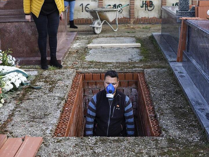 Ein Leichenbestatter in Spanien bereitet ein Grab vor während der Beerdigung einer 86-jährigen Frau mitten in der Corona-Krise.
