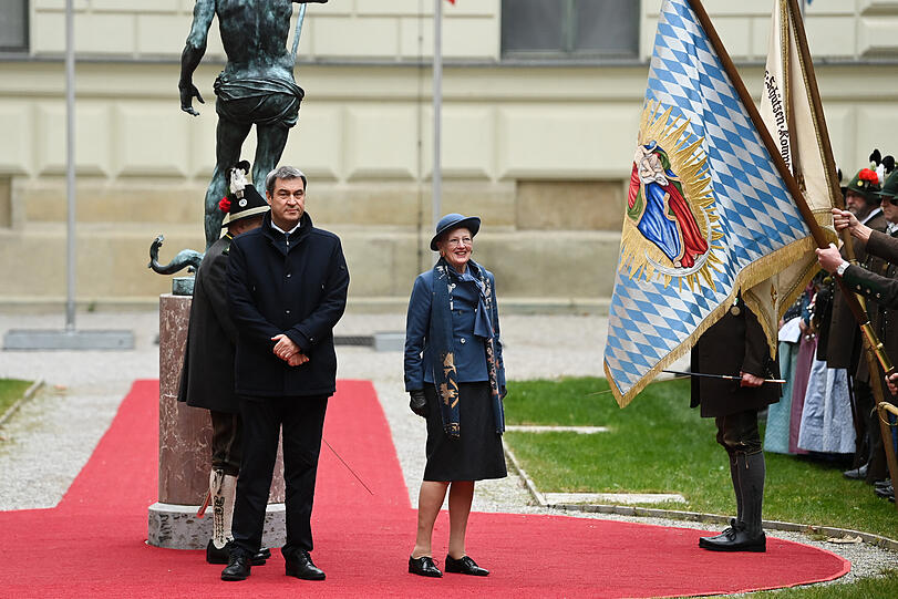 Ministerpräsident Markus Söder und Königin Margrethe II. von Dänemark laufen über den roten Teppich vor der Residenz.