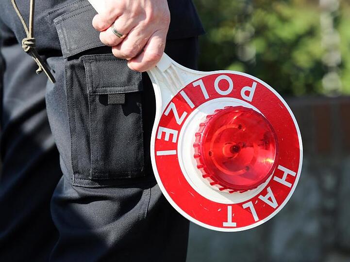 Ein Polizeibeamter hält eine Polizeikelle in der Hand. Foto: Bodo Marks/Archivbild