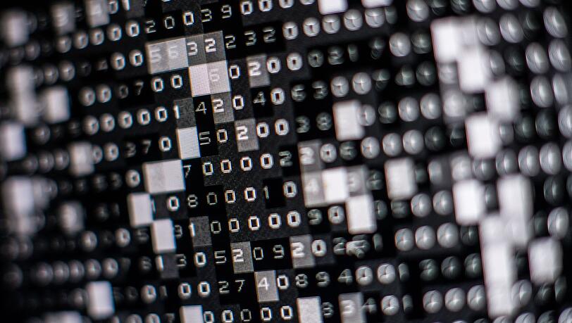 Eine fiktive Hackersoftware verschlüsselt in einer Maske auf dem Bildschirm Daten auf einer Festplatte.