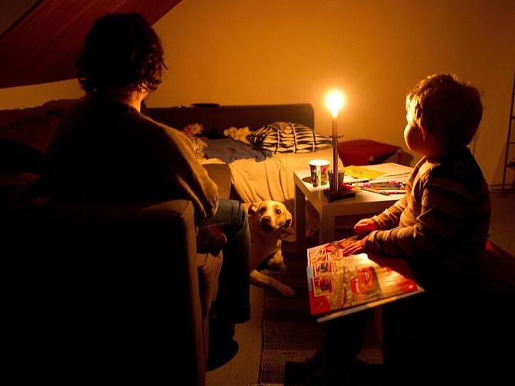 Eine Mutter sitzt mit ihrem Sohn in ihrer abgedunkelten Wohnung.
