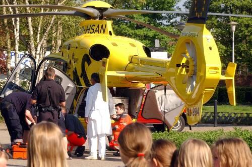 Schaulustige beobachten, wie eines der Opfer des Hallenbad-Unglückes in einen Hubschrauber verladen wird.