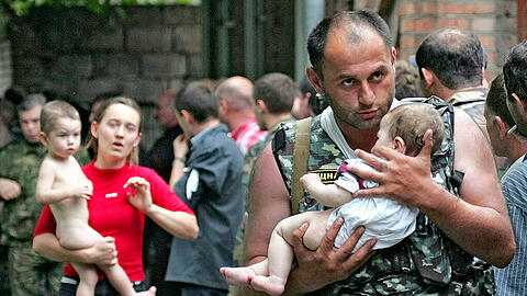 Ein Soldat trägt am 2. September 2004 ein Baby aus der besetzten Schule. Einen Tag später eskalierte die Situation; mehr als 330 Menschen starben.