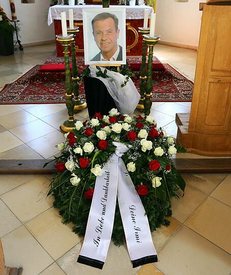 Vor dem Altar stehen ein Foto des Opfers und ein Kranz mit Rosen.