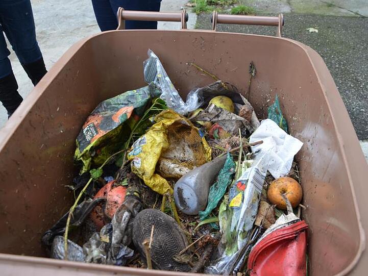 Diverser Plastikunrat liegt in einer braunen Biotonne des Abfallwirtschaftsbetriebs München (AWM). Foto: /AWM/dpa