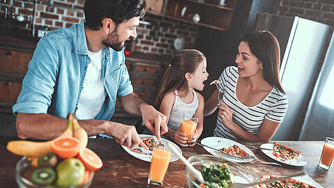 Eine junge Familie mit einer selbst zubereiteten Pizza.