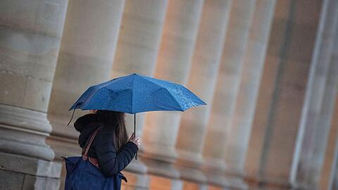Eine Passantin geht bei Regen durch die Stadt.