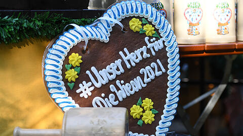 Ein Lebkuchenherz mit der Aufschrift "Unser Herz für die Wiesn 2021" steht zum Start der "WirtshausWiesn 2021" am Viktualienmarkt neben einem Schlegel zum Anzapfen.