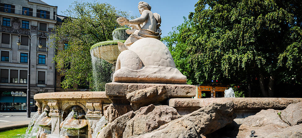 Hier am Wittelsbacher Brunnen hat sich seit einigen Jahren ein kleiner Pumuckl aus Bronze versteckt. K&ouml;nnen Sie ihn entdecken?