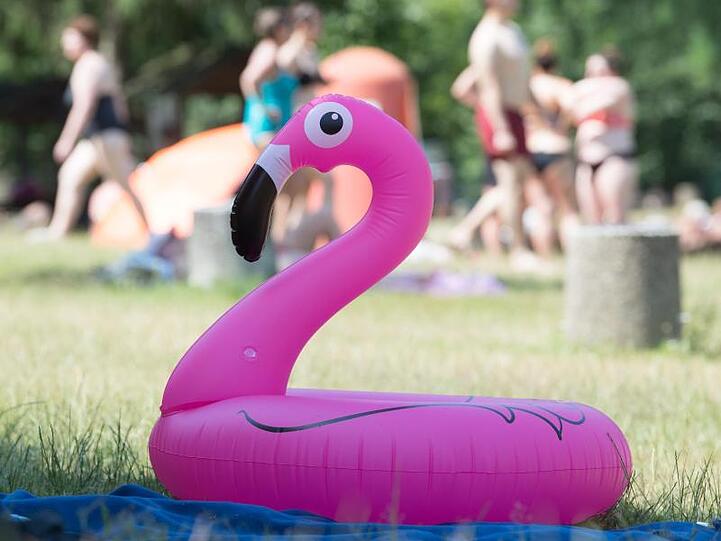 Ein Schwimmring liegt in einem Freibad auf einer Liegewiese. Eine Hitzewelle rollt auf Deutschland zu.