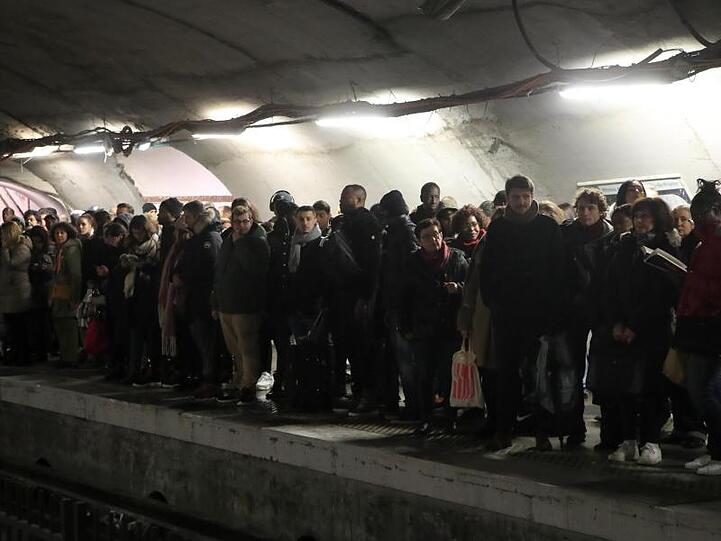 Pendler warten an einem Bahnsteig in Paris vergeblich auf eine U-Bahn.