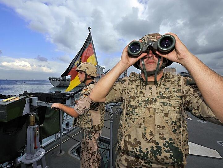 Deutsche Marine-Soldaten halten an Bord der Fregatte "Karlsruhe" an einem Maschinengewehr Wache.