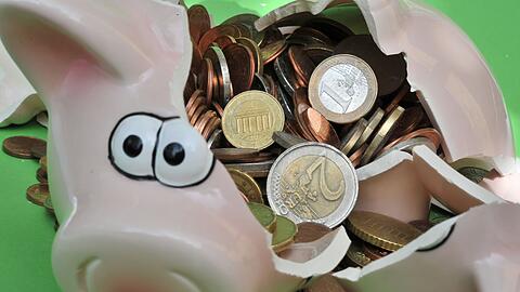Ein zerbrochenes Sparschwein mit Euromünzen.