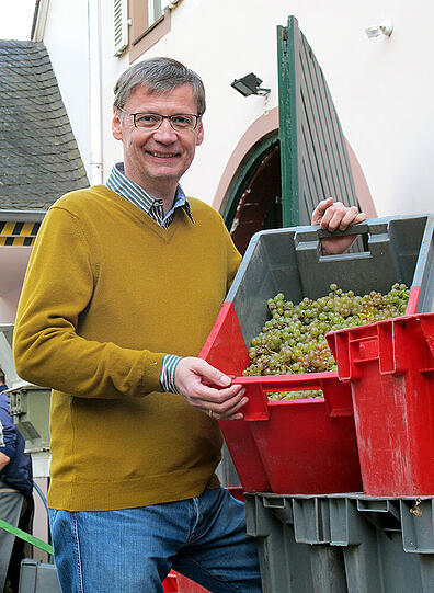 Jauchs Leidenschaft ist der Wein: Hier zeigt er stolz die Trauben auf seinem Weingut in Kanzem (Landkreis Trier-Saarburg).