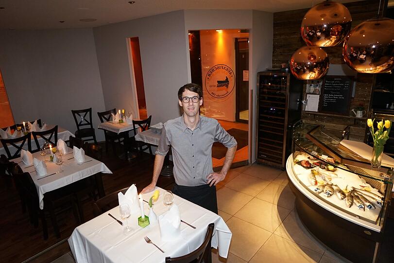 Inhaber Sebastian Wolf vor dem zentralen Blickfang im Auenfischer: der Vitrine mit frischen Fisch.