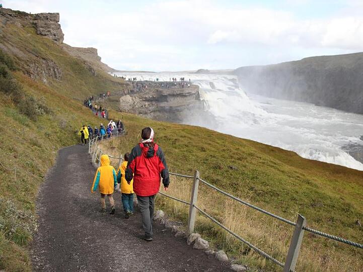Touristen wandern zum Wasserfall Gullfoss.