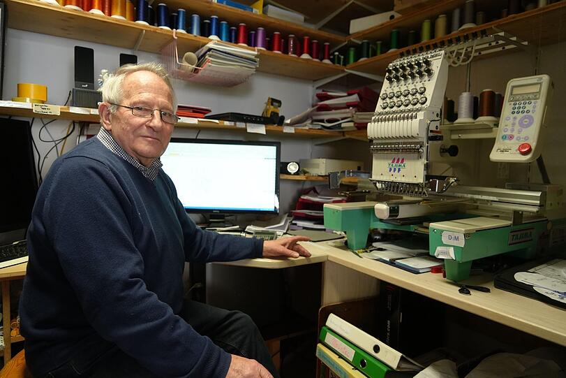 Rolf Zoller (84) hat eine Ladenhälfte für Ursula Fröhmer freigeräumt. Er bestickt seit 45 Jahren Vereinsfahnen - oder Logos in Arbeitskleidung.
