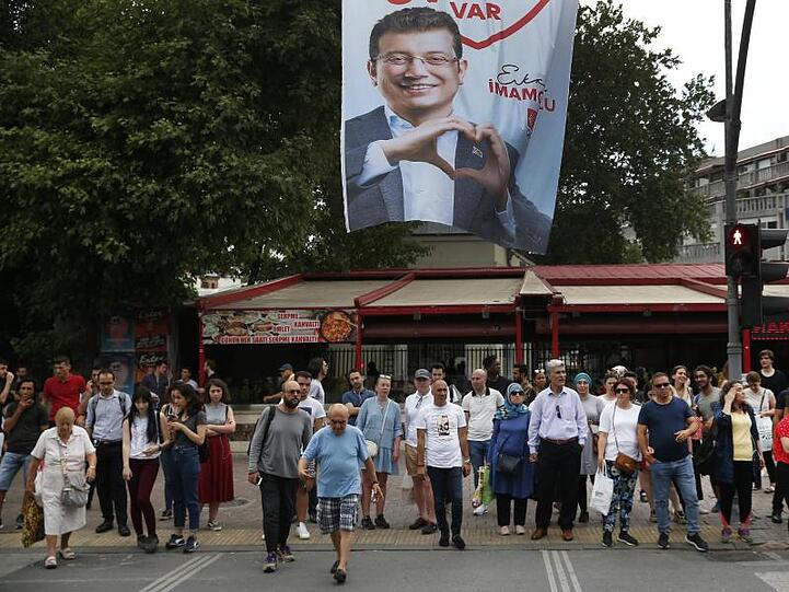 Menschen gehen unter einem Wahlplakat des Bürgermeisterkandidaten Imamoglu der Mitte-Links-Partei CHP entlang. Imamoglu hatte die Bürgermeisterwahl in Istanbul am 31. März 2019 knapp vor seinem Herausforderer Yildirim gewonnen. Allerdings annullierte die Hohe Wahlkommission die Abstimmung und ordnete eine Wiederholung am 23. Juni 2019 an.