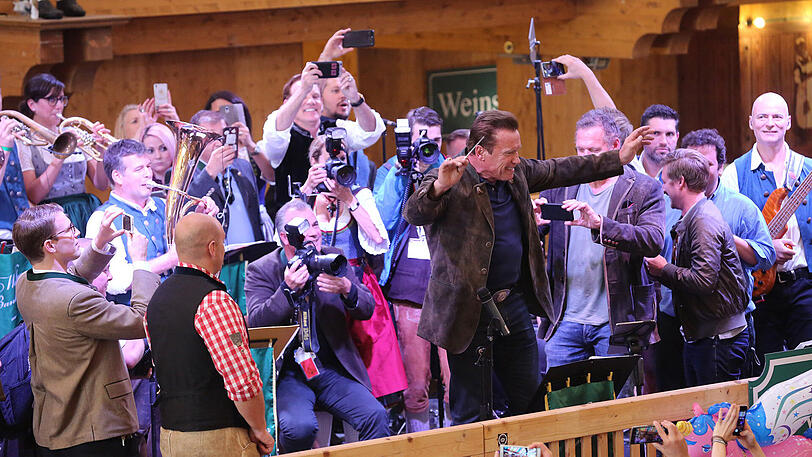 Erst eine kühle Maß, danach Dirigieren auf der Bühne: Die Bilder vom Schwarzenegger-Besuch im Schützen-Festzelt.