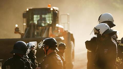 Polizisten stehen im Hambacher Forst neben einer Planierraupe.