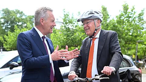 Mit Helm und Fahrrad kommt Stephan Weil (r) zur Wahl, bei der auch Christian Wulff zu Gast ist.