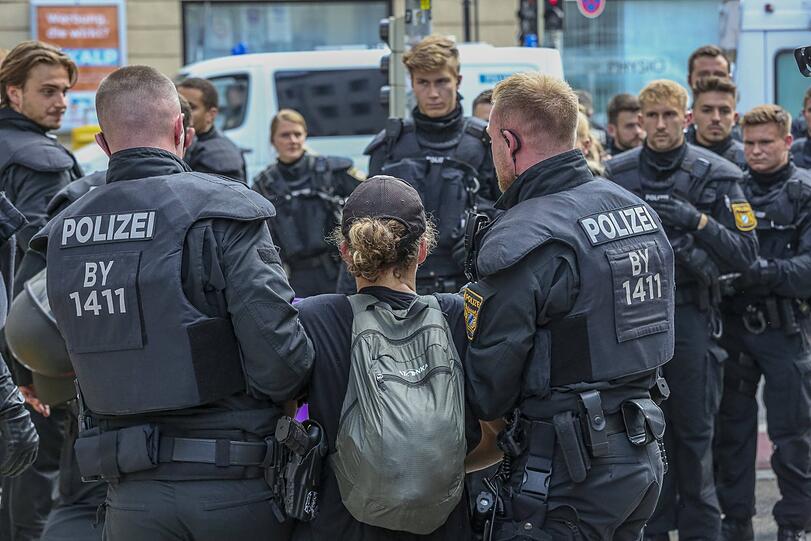 Polizisten tragen eine Aktivistin weg.