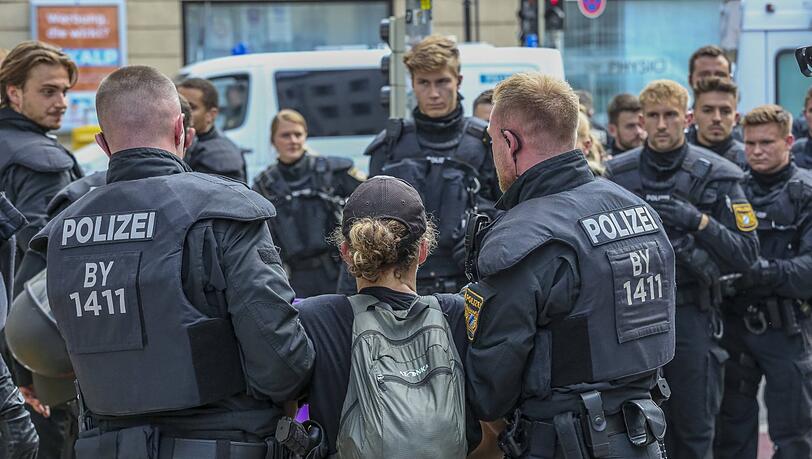 Polizisten tragen eine Aktivistin weg. Polizisten tragen eine Aktivistin weg.