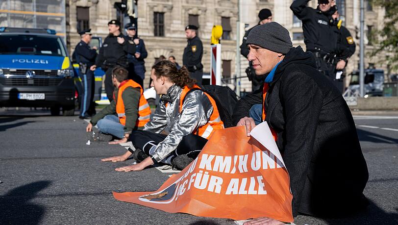 Klima-Aktivisten kleben sich am Stachus auf der Straße fest und blockieren dadurch den Verkehr. Darunter auch Wolfgang Metzler (r.). Klima-Aktivisten kleben sich am Stachus auf der Straße fest und blockieren dadurch den Verkehr. Darunter auch Wolfgang Metzler (r.).