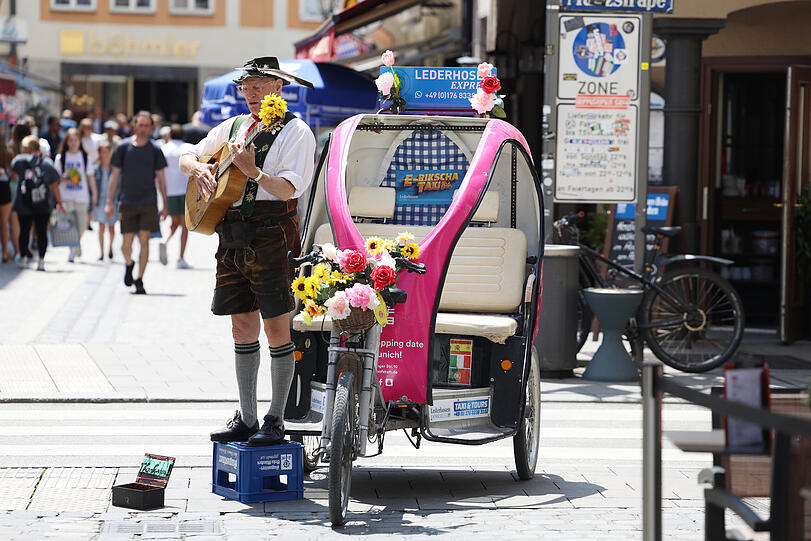 Stilleben am Platzl: Mit Tracht, Gitarre und Augustiner-Tragl wirbt dieser Herr um Touristen für seinen „Lederhosn-Express“.