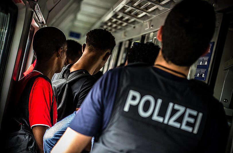 Der Bundespolizist Bastian K. geleitet am 09.09.2014 im gestoppten Eurocity in Rosenheim zahlreiche Flüchtlinge in Richtung Bahnsteig. Der sprunghafte Anstieg der Flüchtlingszahlen in Deutschland stellt die Bundespolizei vor große Herausforderungen.