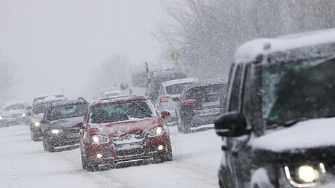 Starker Schneefall behindert den Verkehr auf einer Landstraße.