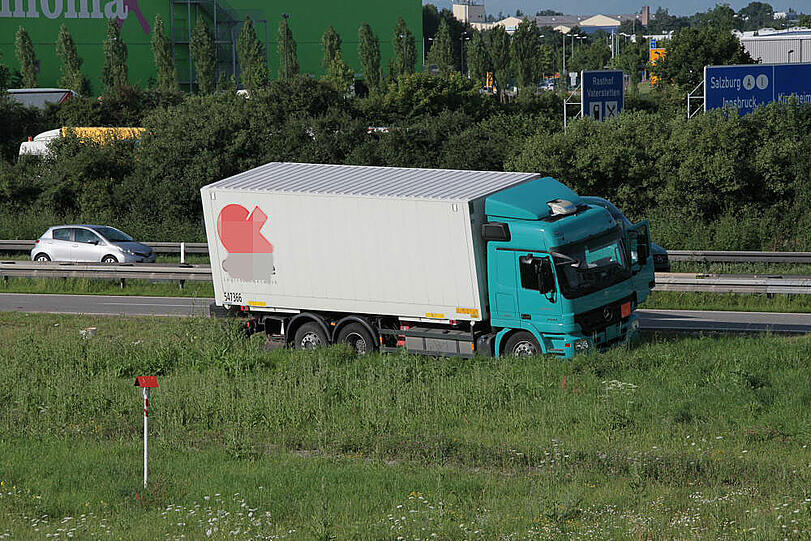 Vermutlich weil er zu schnell auf die Autobahn fährt, kommt ein Laster in der Kurve von der Fahrbahn ab und fährt in die Leitplanke. Sein Hänger kippt um.