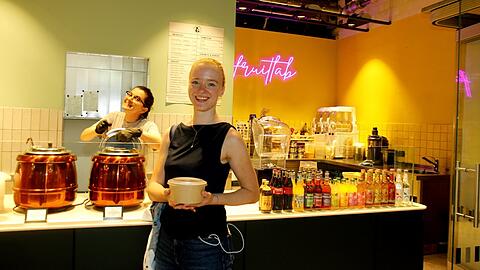 Im Sperrengeschoss unterm Sendlinger Tor sind - ein halbes Jahr nach der Eröffnung - die Geschäfte gut angelaufen. Hier nimmt Studentin Amelie Lintmeier (21, M.) auf dem Heimweg im "Vince & Wiens" ein Bean Masala Curry mit. Im "fruitlab" hinten presst die Italienerin Valeria (l.) fortwährend frische Säfte.