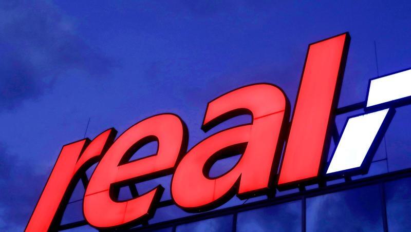 Das Real-Logo leuchtet am Morgen auf dem Dach eines Real Warenhauses in Köln. Das Real-Logo leuchtet am Morgen auf dem Dach eines Real Warenhauses in Köln.
