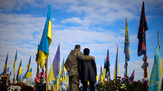 Die Eltern eines kürzlich getöteten ukrainischen Soldaten stehen auf einem Friedhof in Charkiw.
