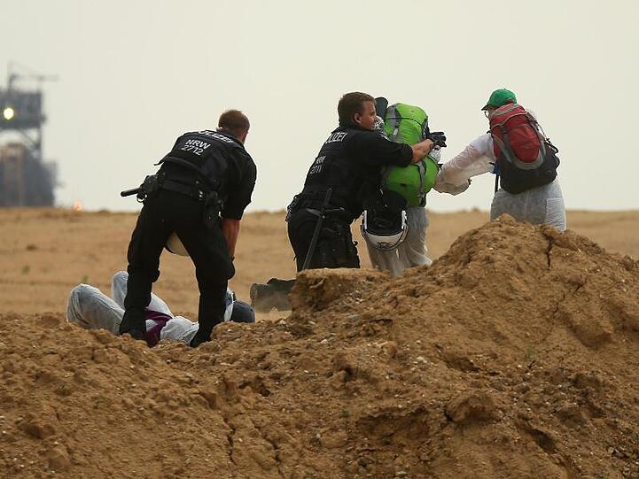 Polizisten versuchen Aktivisten am Betreten des Tagebau Garzweiler zu hindern.
