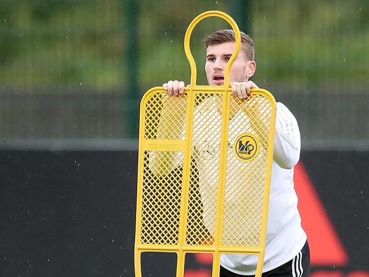 Timo Werner hält sich beim Dehnen an einem Trainingsdummy fest.