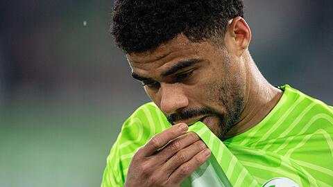 FußballWolfsburgs Paulo Otavio beißt nach seiner verletzungsbedingten Auswechselung in sein Trikot.