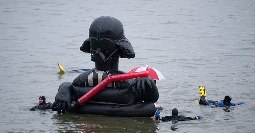 Die Teilnehmer sprangen von einem Feuerwehrboot aus in den Rhein, um mehrere hundert Meter flussabwaerts zu schwimmen.