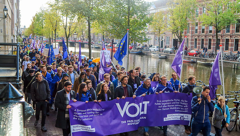 Mitglieder und Anhänger der proeuropäischen Partei Volt ziehen mit Flaggen und Bannern in Amsterdam durch eine Straße. Mitglieder und Anhänger der proeuropäischen Partei Volt ziehen mit Flaggen und Bannern in Amsterdam durch eine Straße.